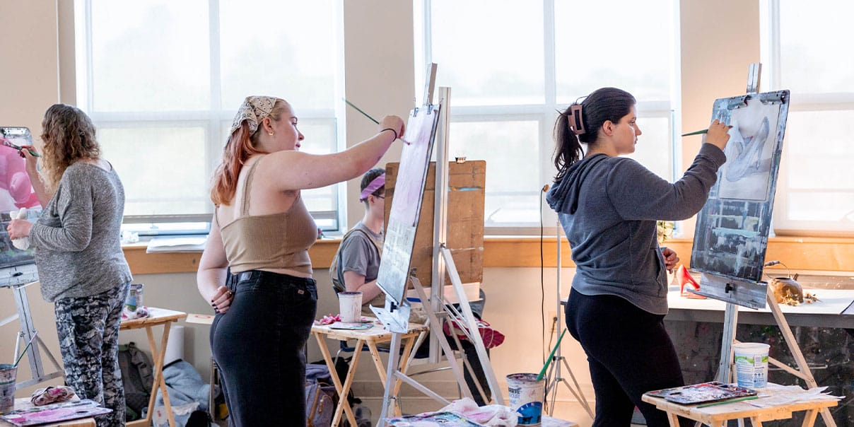 Three CCV art students painting on canvases.